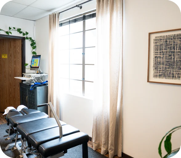 Momma's Chiro treatment room, with an adjusting table beside a curtained window