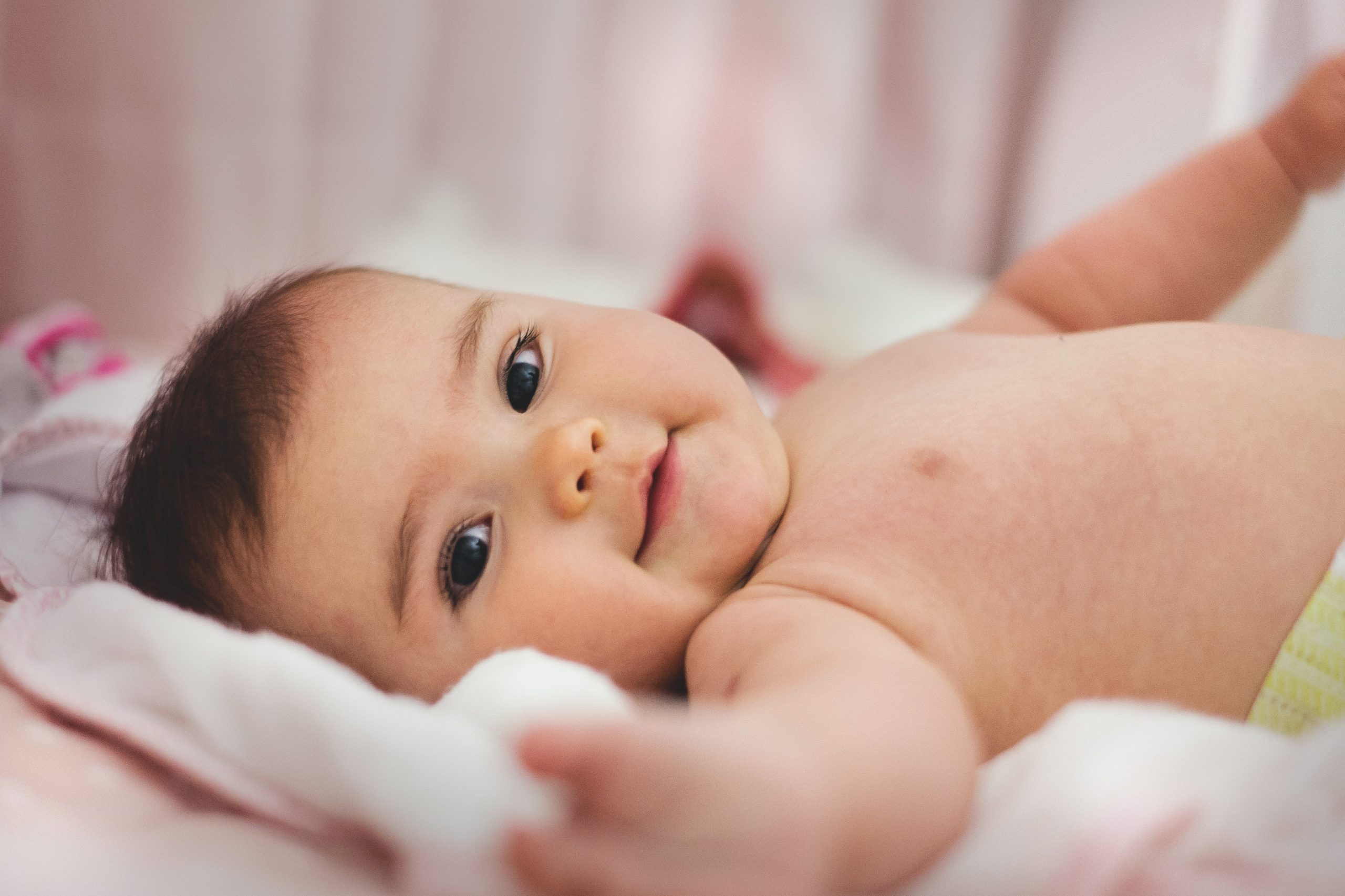 baby-lying-on-pink-bed-1556706-scaled